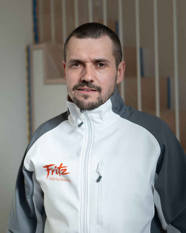 Henryk Knichalla, Leiter Bauausführung, im Fritz Malerfachbetrieb Arbeitsjacke vor einer unfertigen Holztreppe